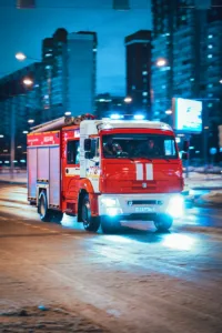 a red fire truck driving down a street at night