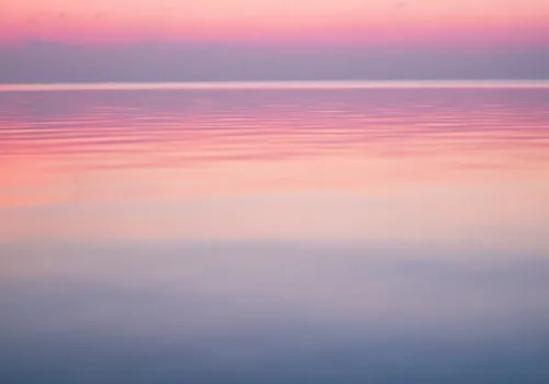 Pastel colored sky over calm ocean water
