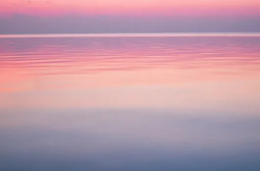 Pastel colored sky over calm ocean water